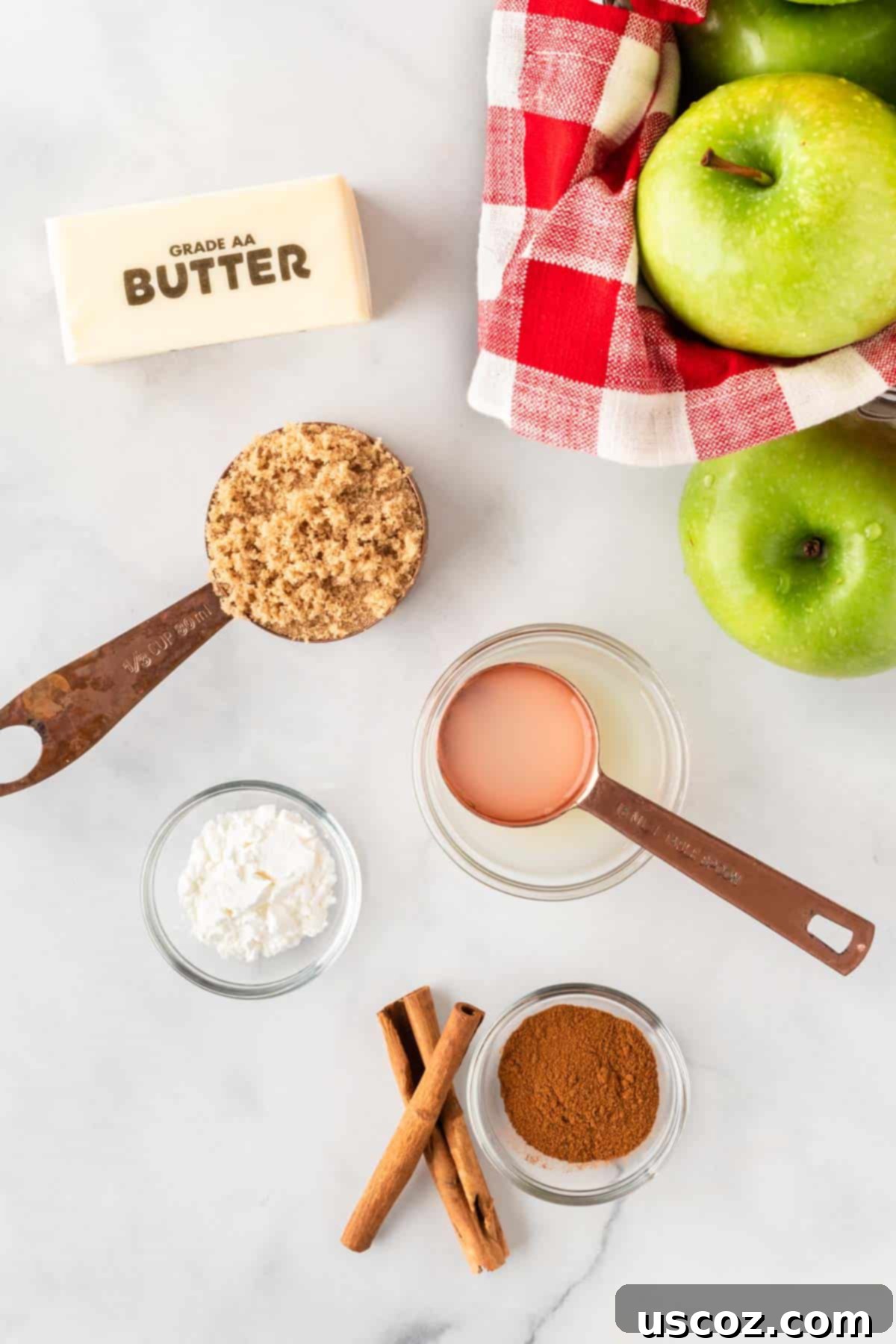 Warm Baked Cinnamon Apples 3 All essential ingredients laid out on a wooden surface, ready to make baked cinnamon apples: fresh apples, brown sugar, cornstarch, butter, cinnamon, and a lemon.