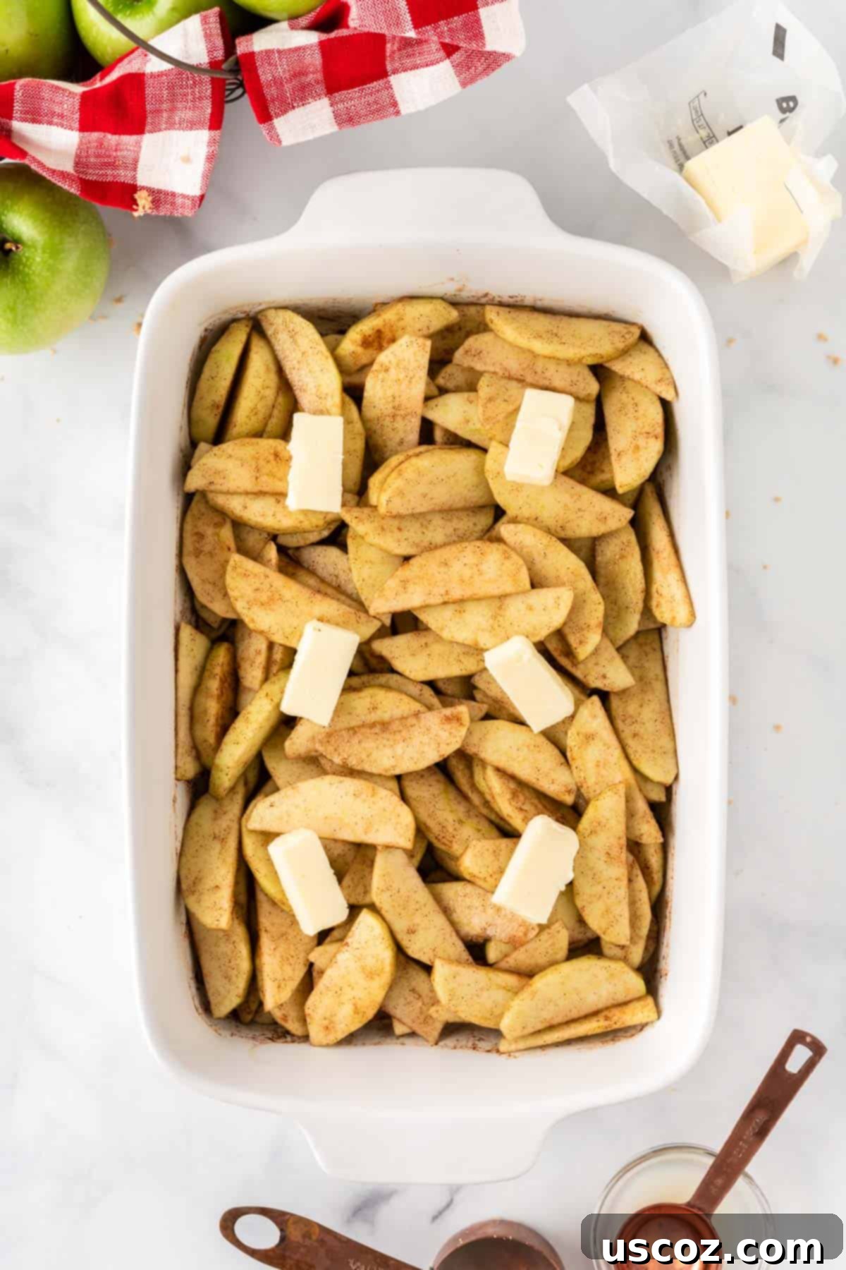 Warm Baked Cinnamon Apples 8 Small pieces of salted butter strategically placed over the seasoned apple slices in the baking dish.