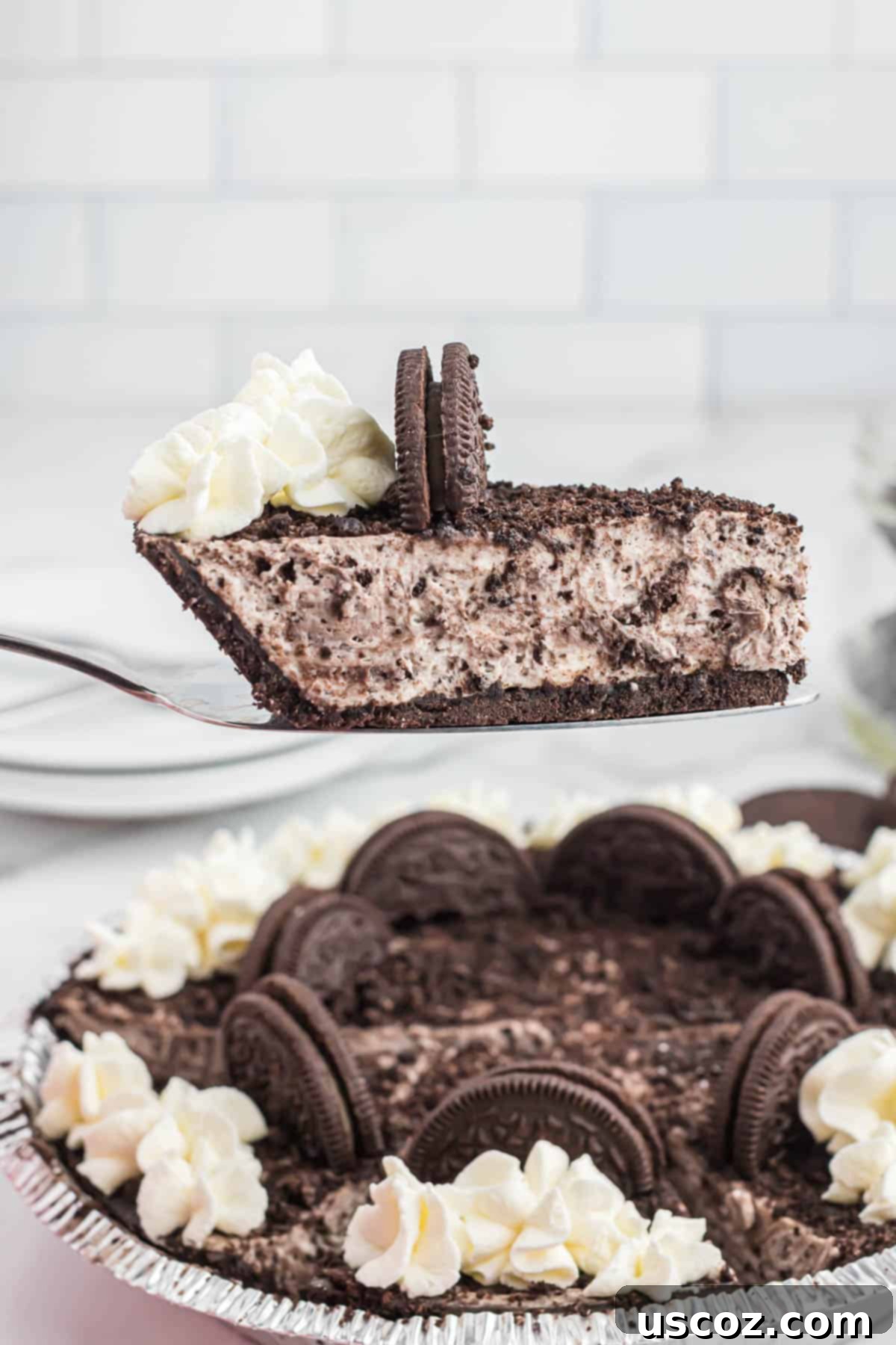 Oreo Bliss Pie 13 A hand reaching for a slice of the chilled, ready-to-eat No-Bake Oreo Pie, presented on a decorative stand.