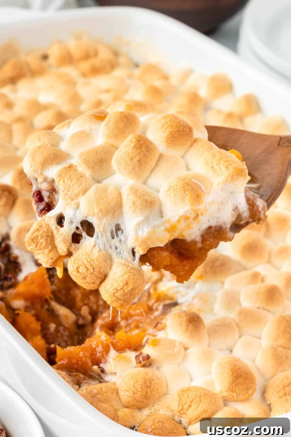 Golden Sweet Potato Marshmallow Bake 2 scooping sweet potato casserole from the dish