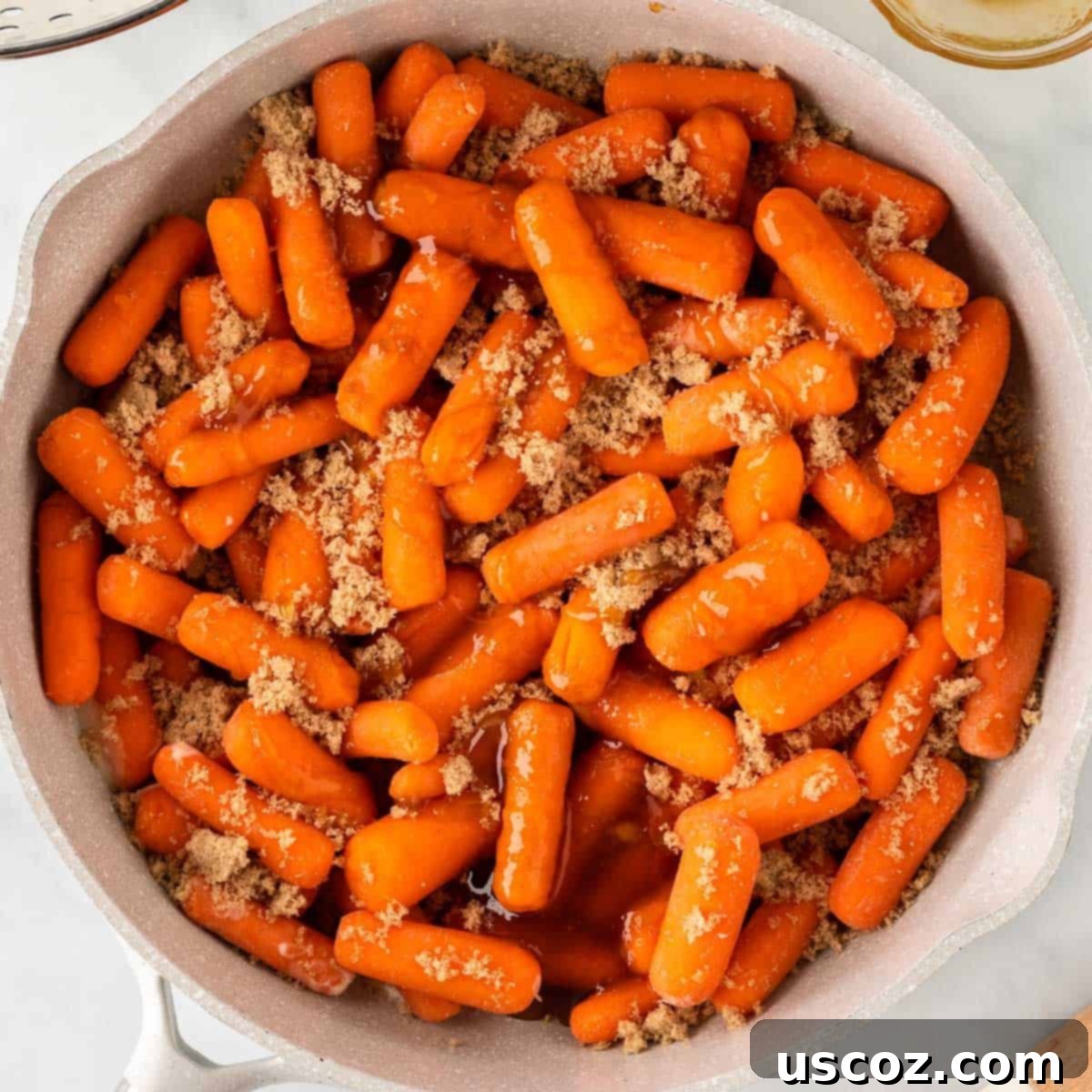 Sweet & Sticky Honey Brown Sugar Carrots 7 baby carrots in a skillet topped with brown sugar