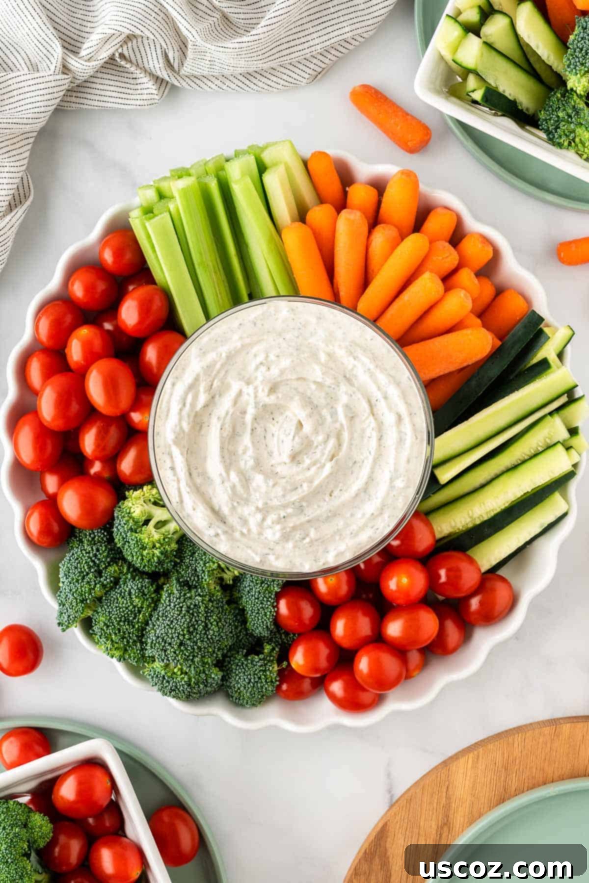 Garden Fresh Dip 10 A large, inviting bowl of creamy veggie dip placed prominently amidst a vibrant arrangement of fresh vegetables like broccoli, cherry tomatoes, celery, and baby carrots, ready for a gathering.