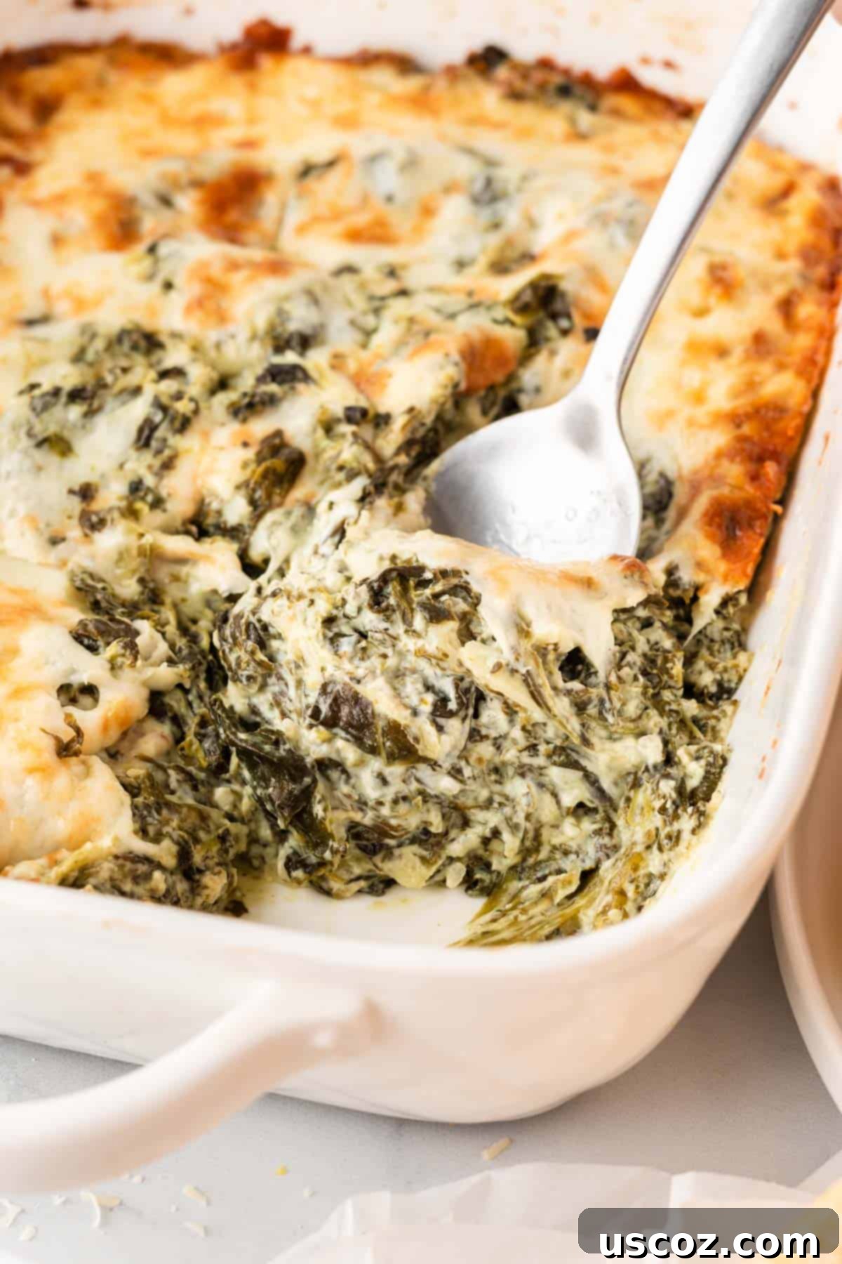 Decadent Creamy Spinach Dip 11 taking a spoonful of spinach dip from the pan