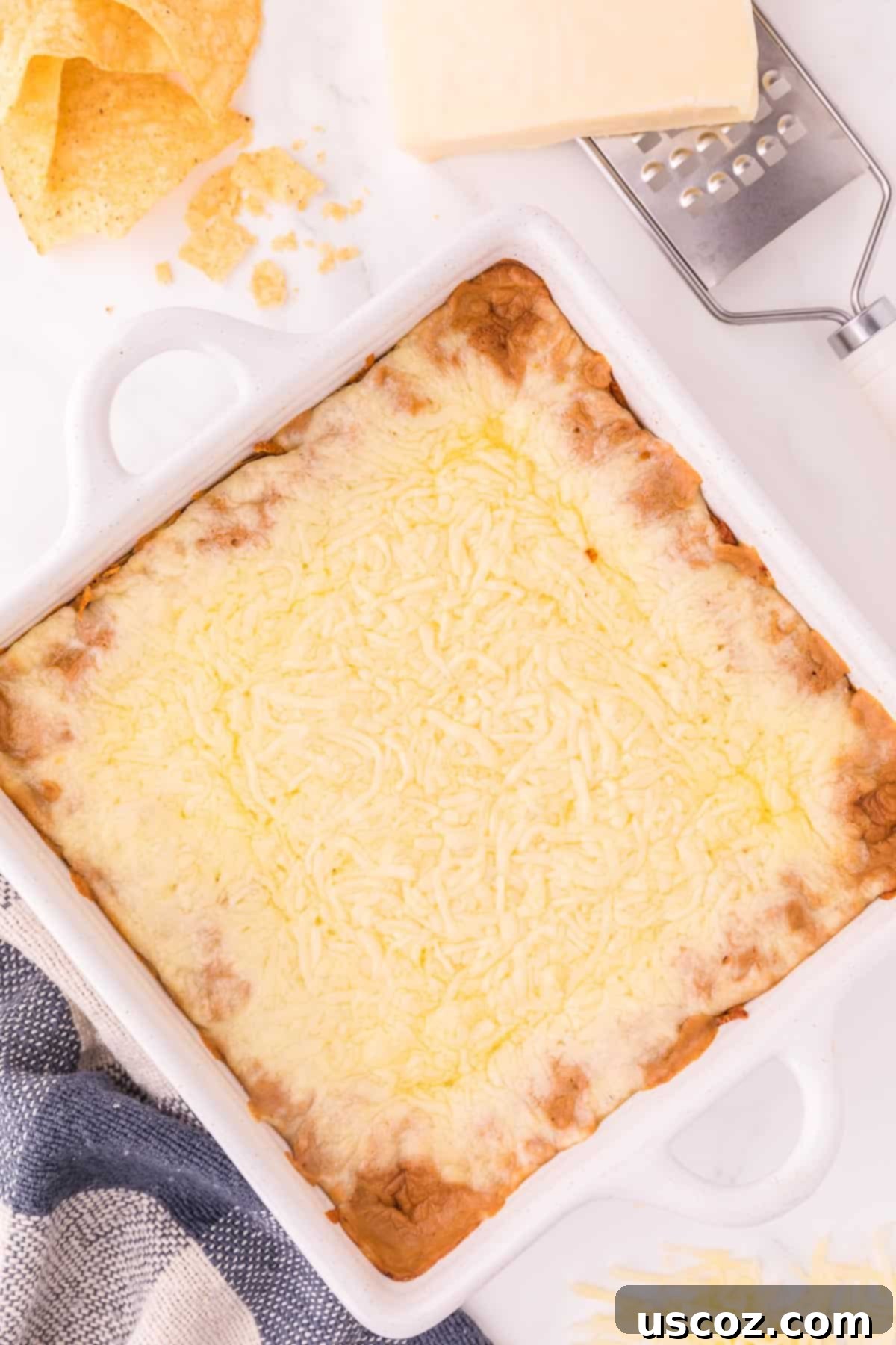 Rich Cream Cheese Bean Dip 7 The bean dip in a baking dish, freshly topped with shredded cheese and ready for the oven