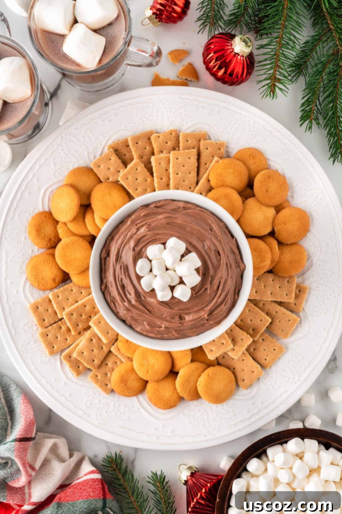 Cozy Chocolate Dip 11 Hot chocolate dip served on a platter with an assortment of Nilla Wafers and graham crackers, ready for dipping.