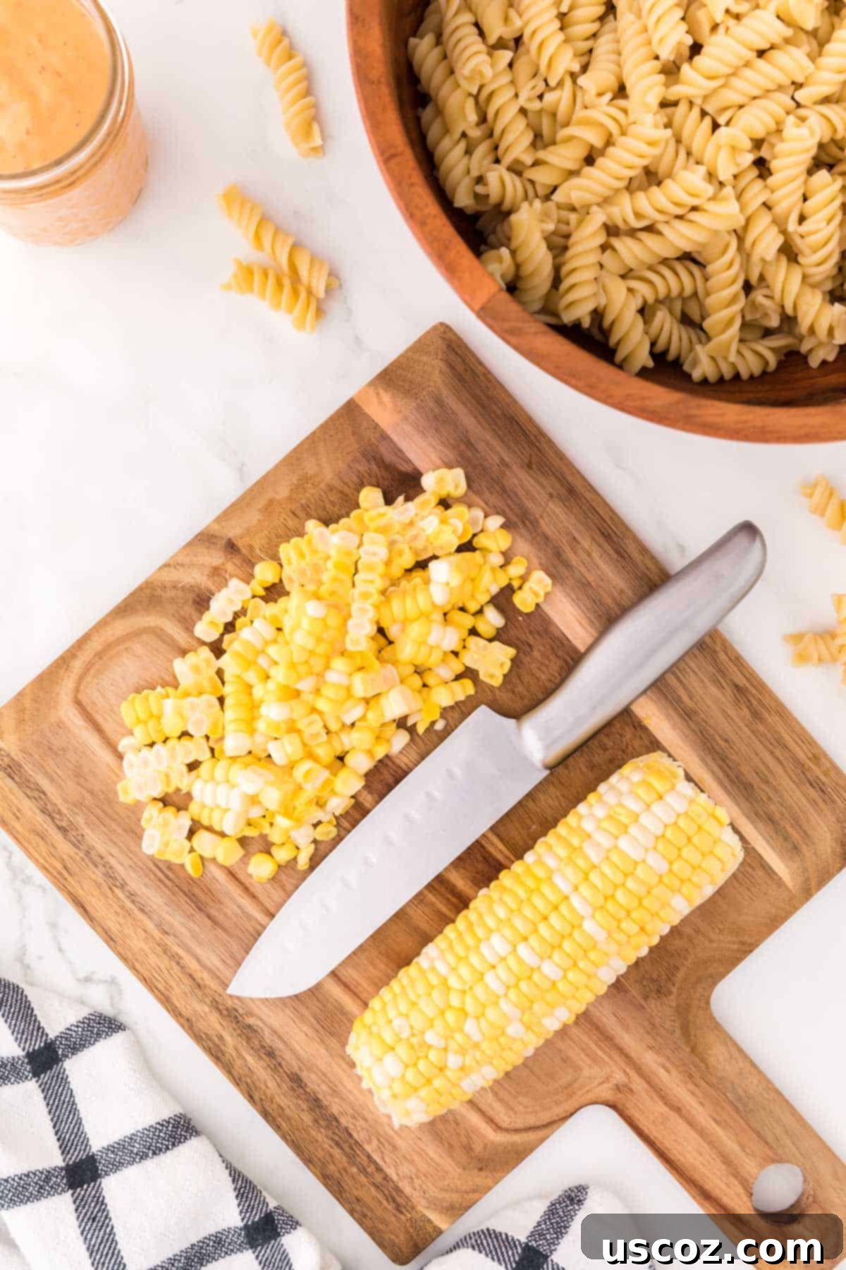 Zesty Southwest Pasta Delight 5 Fresh corn kernels cut from the cob on a wooden cutting board, ready for the pasta salad.