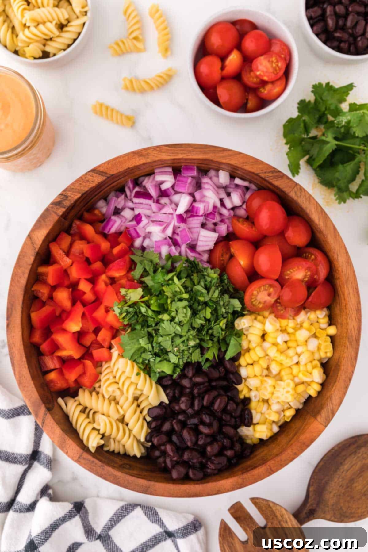 Zesty Southwest Pasta Delight 9 A large mixing bowl filled with all the ingredients for southwest pasta salad before the dressing is added: pasta, corn, black beans, and chopped vegetables.