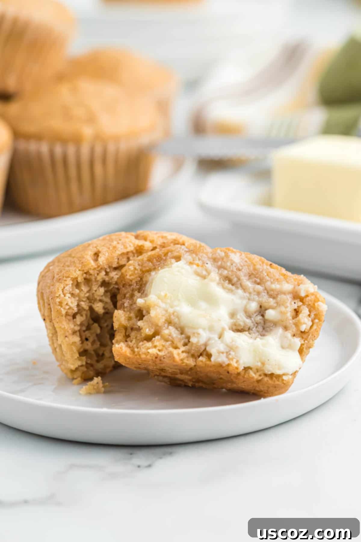 Homestyle Applesauce Muffins 13 An applesauce muffin cut open, revealing its tender, moist crumb, with a pat of butter melting perfectly on top.