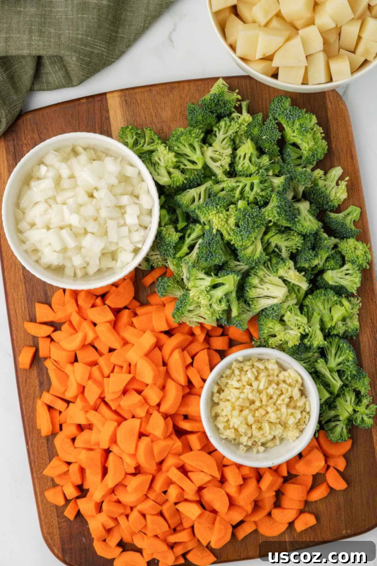 Velvet Veggie Delight 4 A cutting board filled with freshly chopped carrots, onions, garlic, and broccoli florets, meticulously prepared for the creamy vegetable soup recipe.