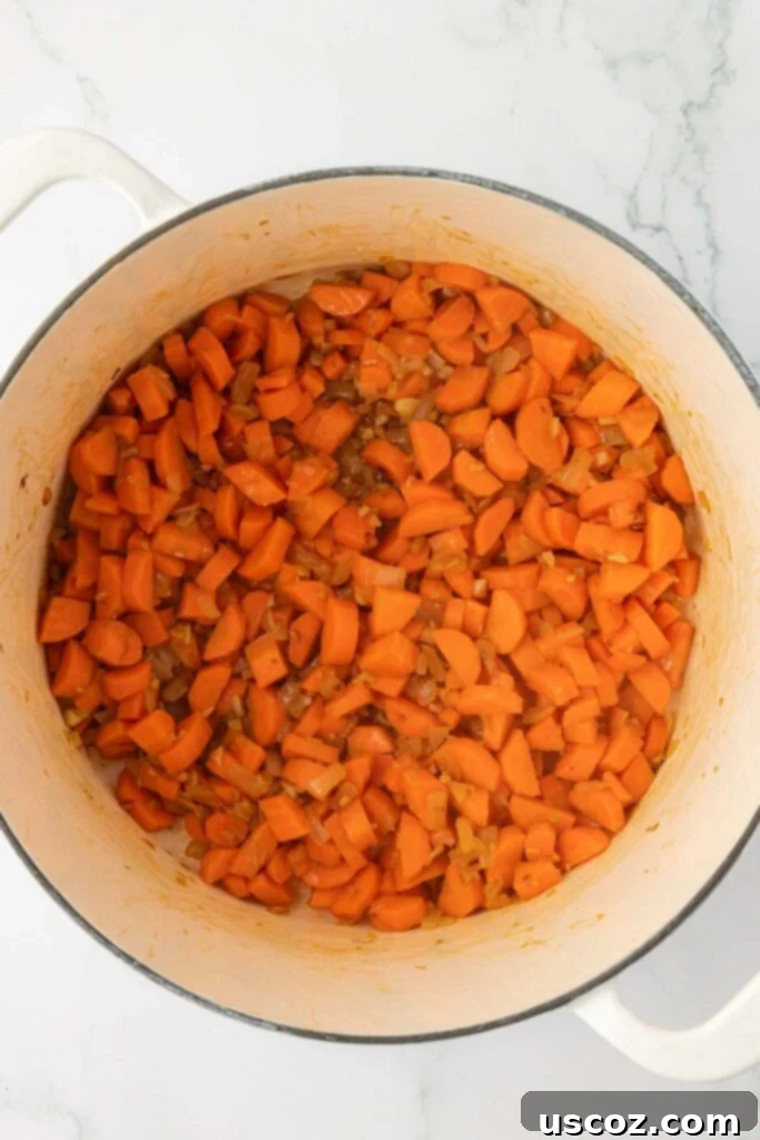Velvet Veggie Delight 8 A close-up view of cooked-down carrots, onions, and garlic in a Dutch oven, beautifully softened and ready for the broth and potatoes.
