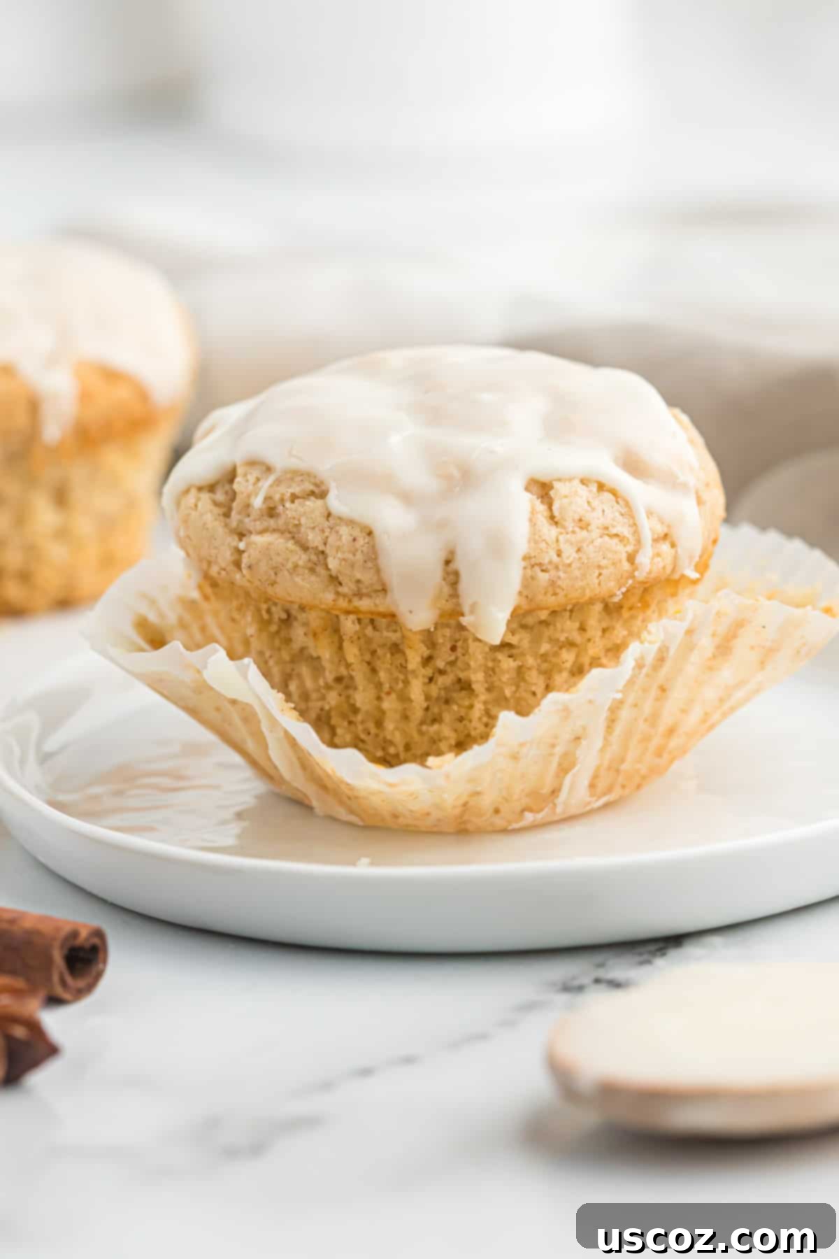 Holiday Eggnog Muffins 11 A single glazed eggnog muffin placed on a white plate, showcasing its fluffy texture and golden-brown hue.