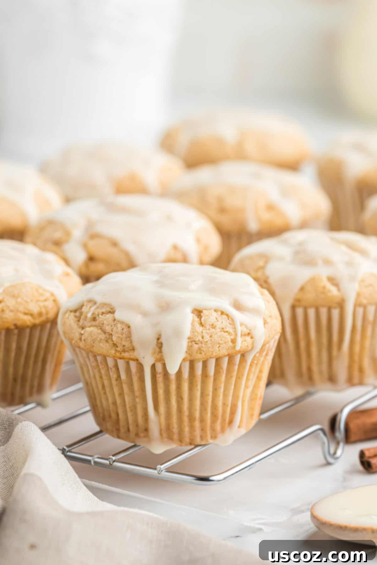 Holiday Eggnog Muffins 3 Glazed eggnog muffins cooling on a wire rack, glistening with sweet icing.