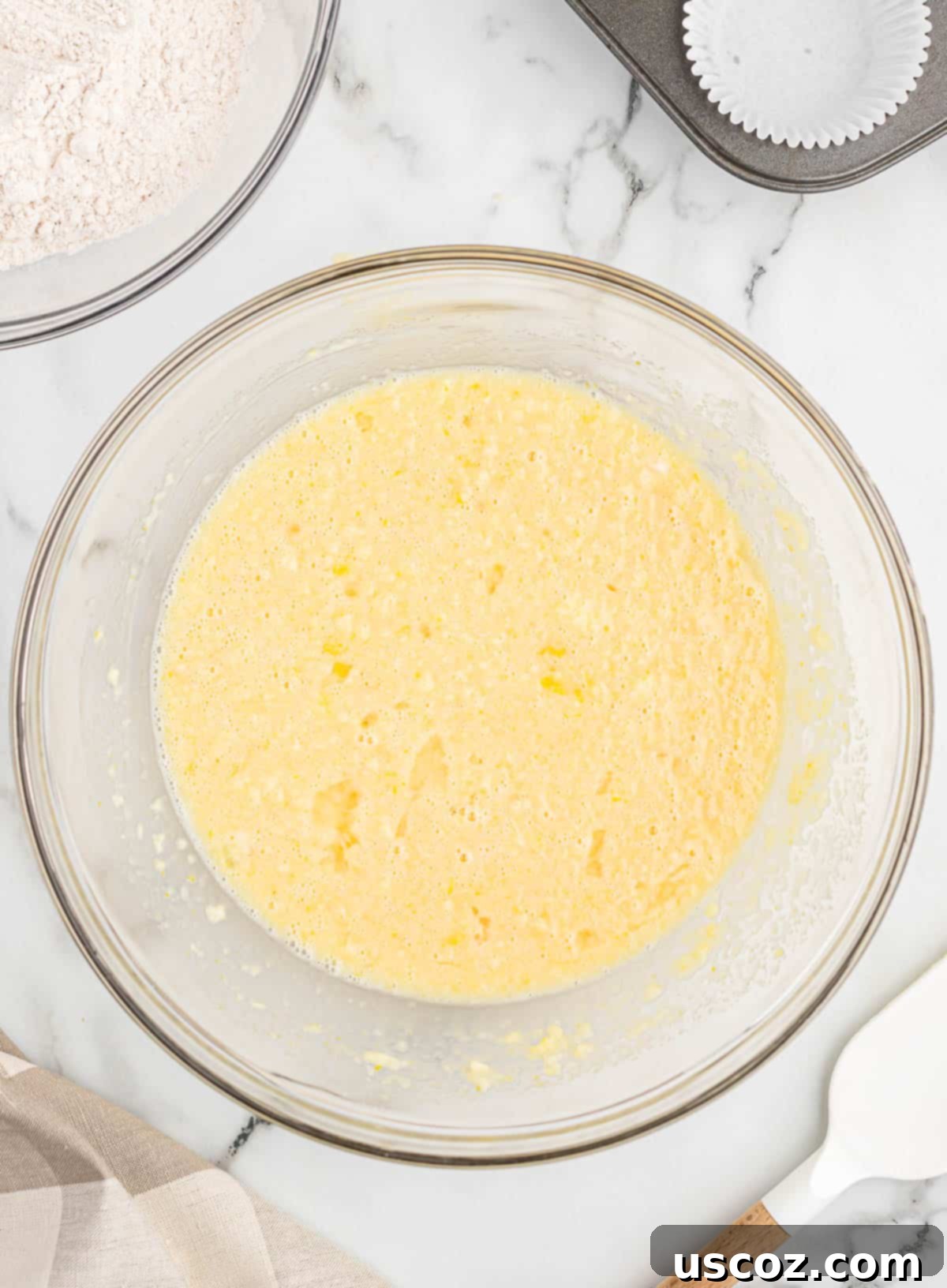 Holiday Eggnog Muffins 5 A bowl filled with the wet ingredients for eggnog muffins, including eggnog, eggs, sugar, and vanilla extract.