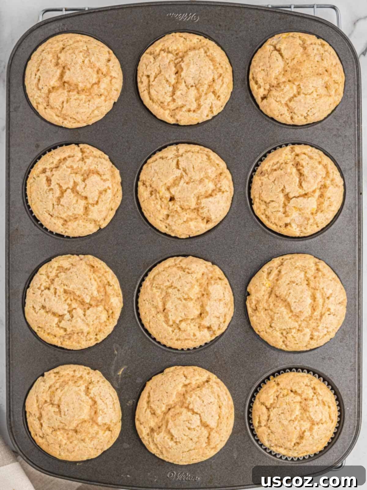 Holiday Eggnog Muffins 8 Freshly baked eggnog muffins cooling in the muffin tin after coming out of the oven.