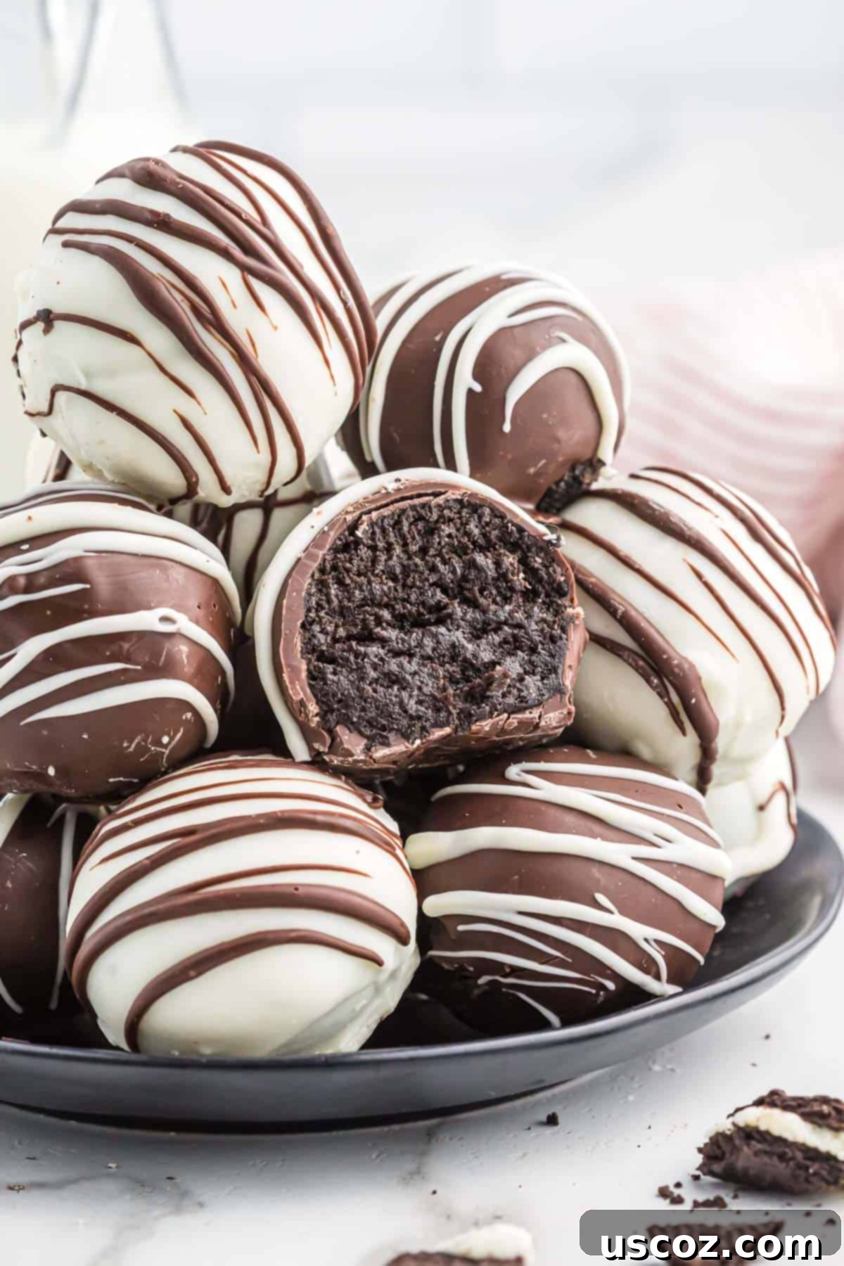 Oreo Truffles 2 Oreo balls on a serving plate, beautifully decorated with dark and white chocolate drizzles.