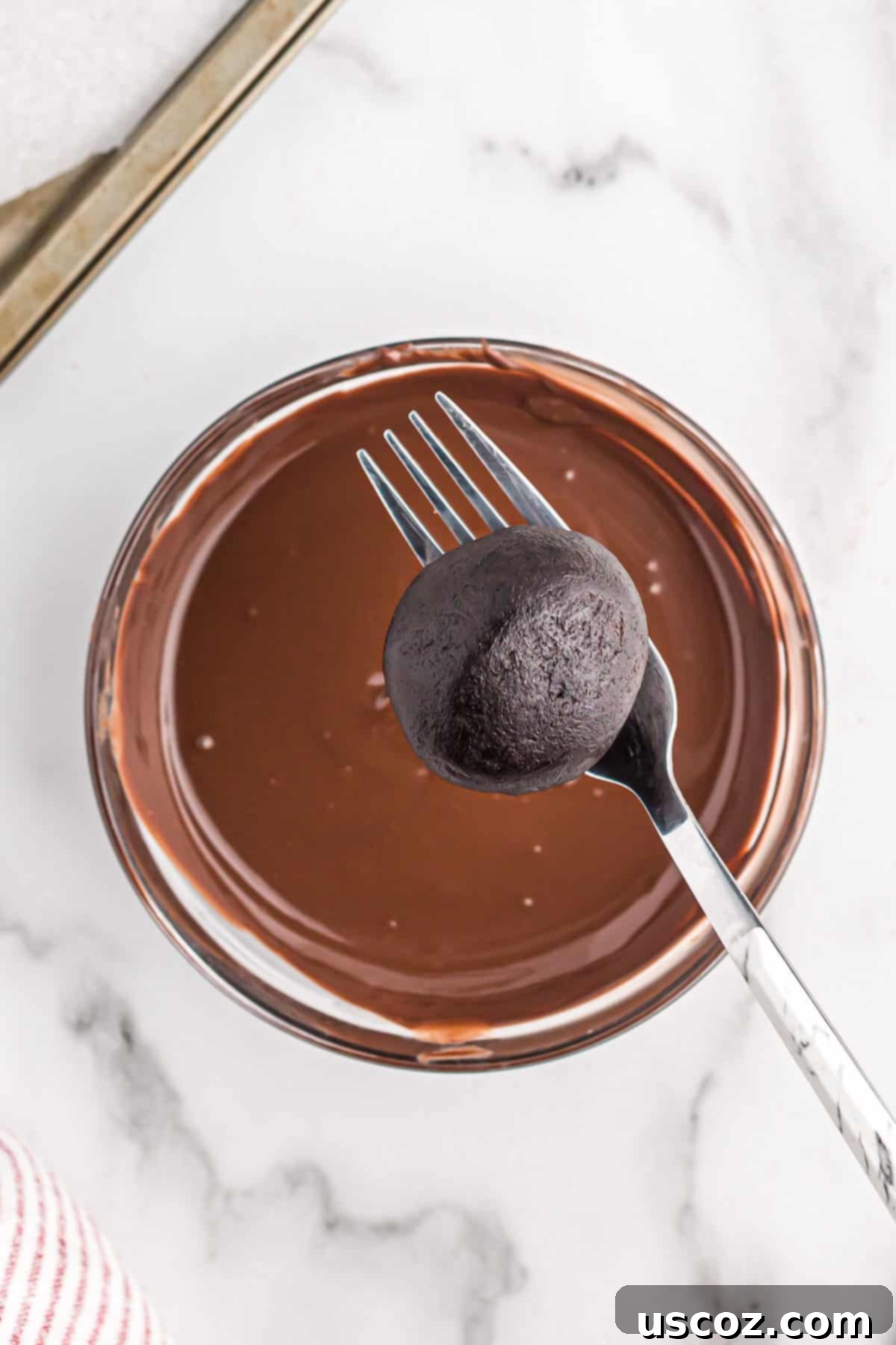 Oreo Truffles 6 A hand carefully dipping an Oreo ball into a bowl of rich, melted dark chocolate, ensuring full coverage.