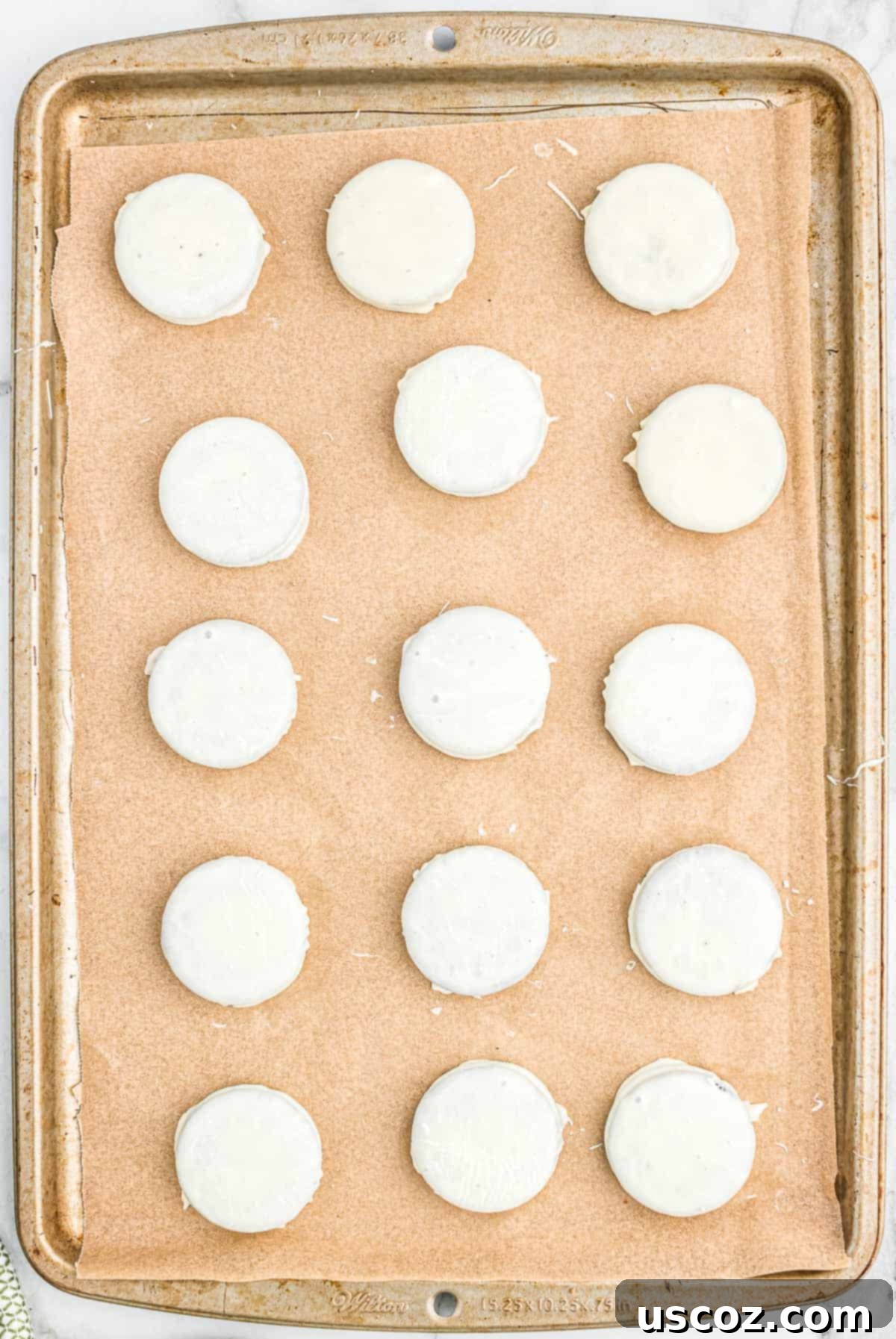 Decadent White Chocolate Oreos 6 white chocolate coated Oreos on a lined baking sheet