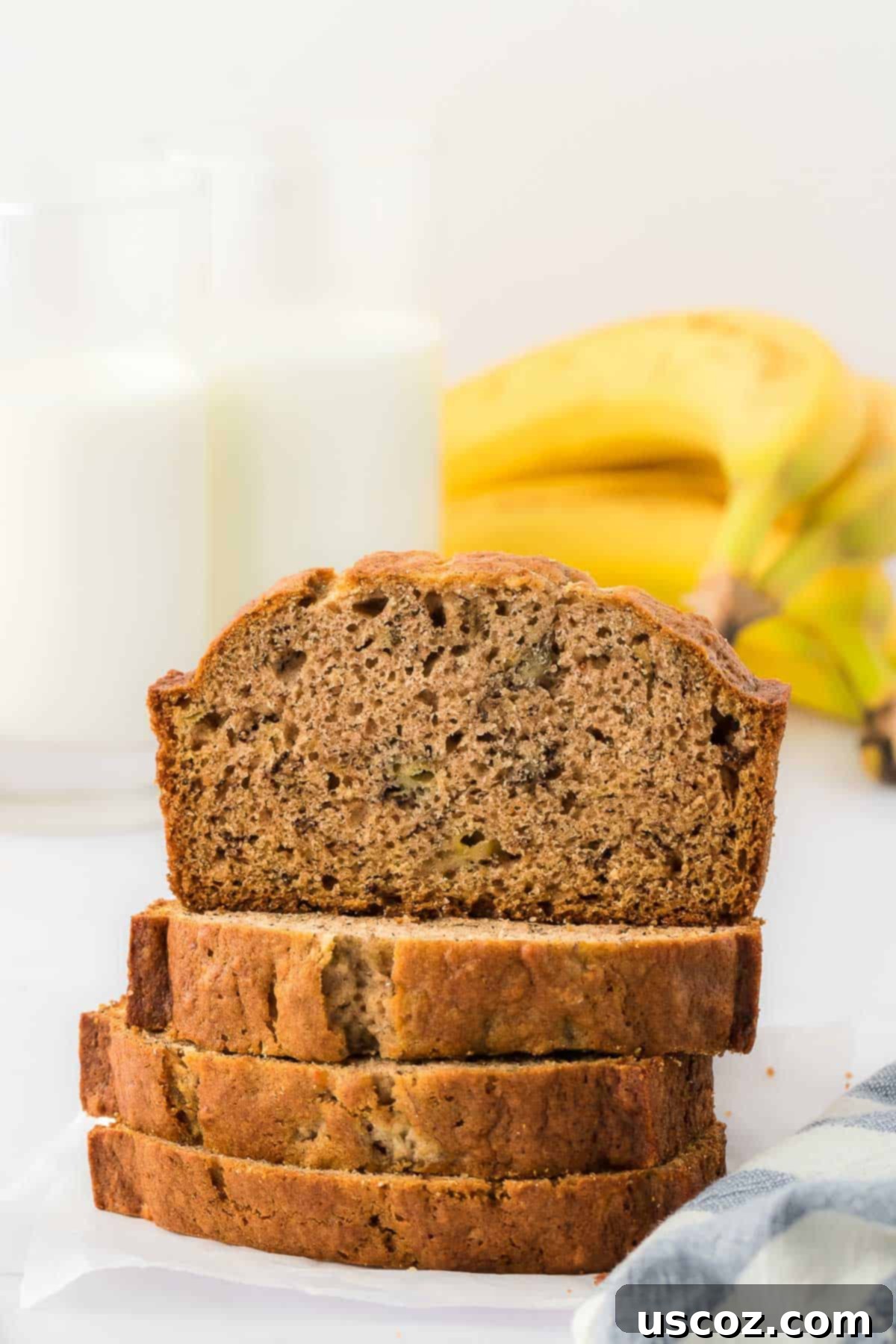 Ultimate Moist Banana Bread 4 Perfectly stacked slices of moist, classic banana bread on a wooden cutting board.