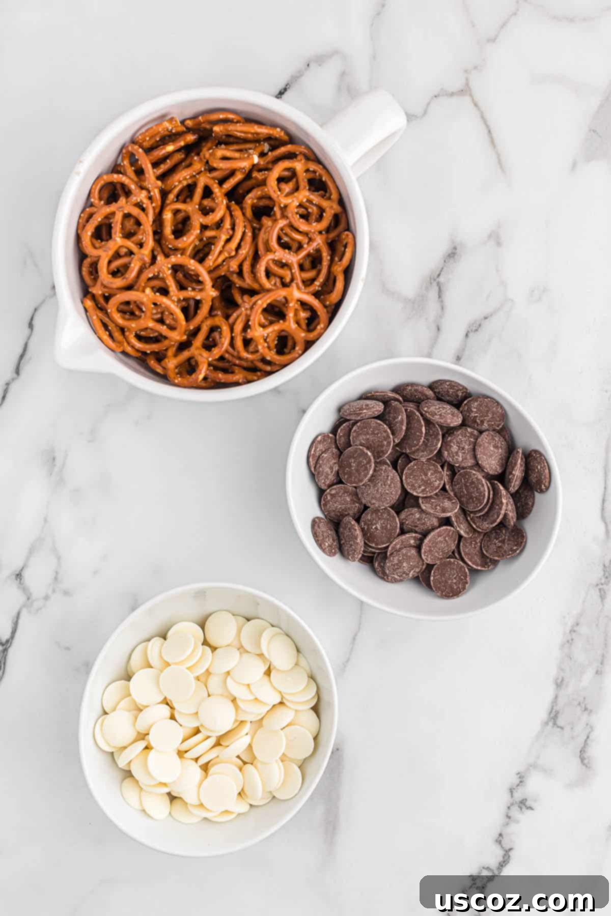 Chocolate Pretzel Perfection 4 The essential ingredients for chocolate covered pretzels laid out: mini pretzels, dark chocolate melting wafers, and white vanilla melting wafers.