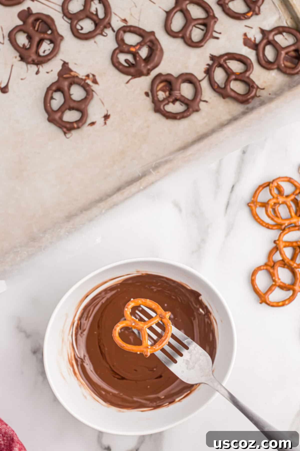 Chocolate Pretzel Perfection 5 A hand holding a mini pretzel over a small bowl of rich melted dark chocolate, ready for dipping.