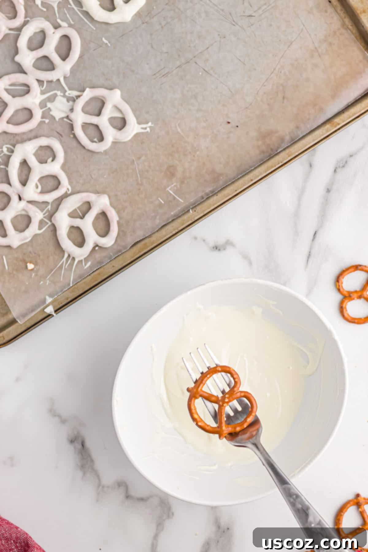 Chocolate Pretzel Perfection 7 A hand holding a mini pretzel over a small bowl of creamy melted white chocolate.