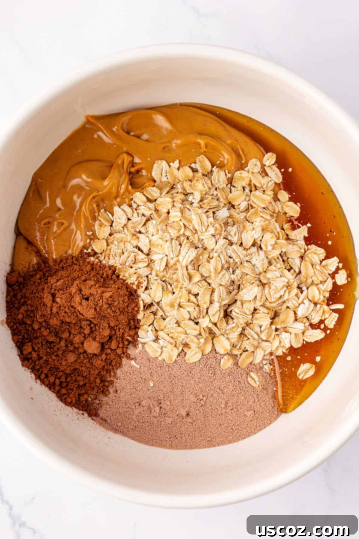 Protein-Packed Chocolate Bars 5 Mixing bowl with creamy peanut butter, honey, rolled oats, chocolate protein powder, and cocoa powder