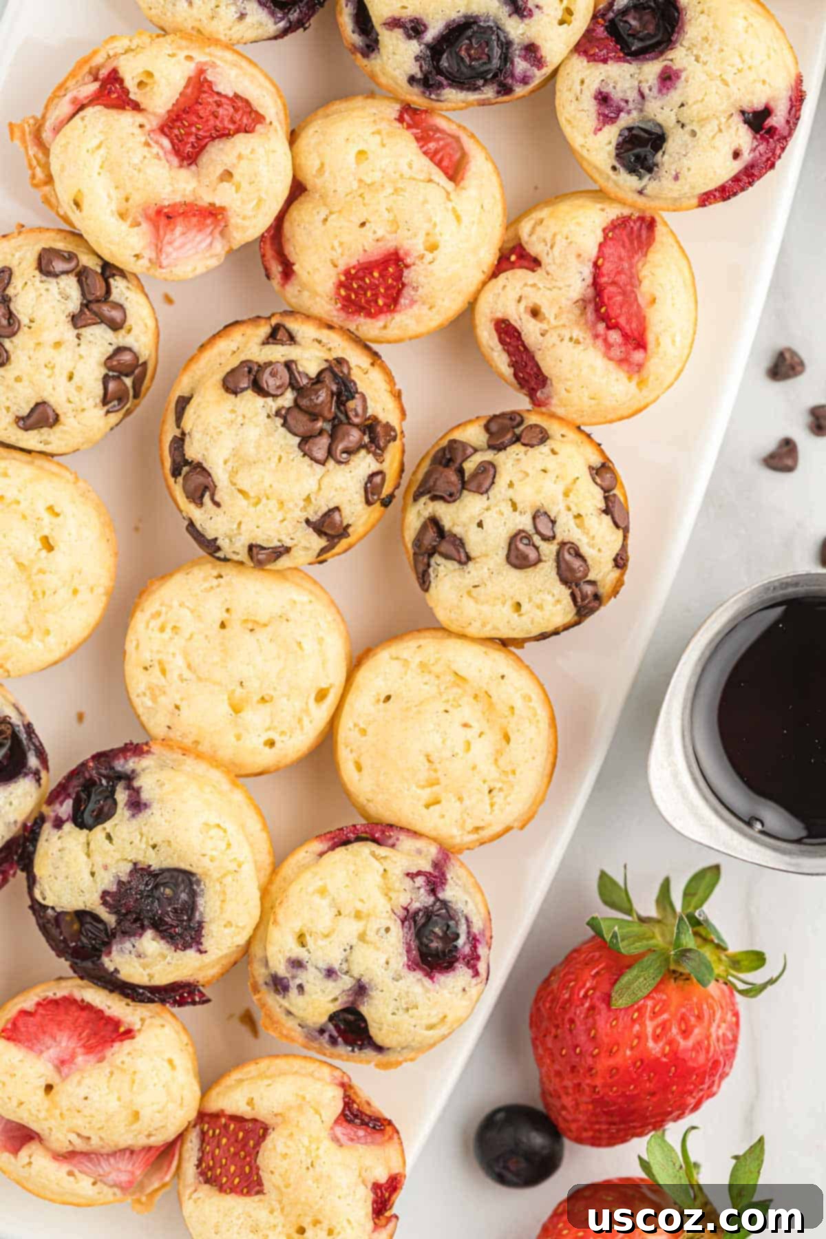Breakfast Pancake Bites 2 A platter of fluffy pancake mini muffins, some topped with blueberries, strawberries, and chocolate chips, ready to be enjoyed.