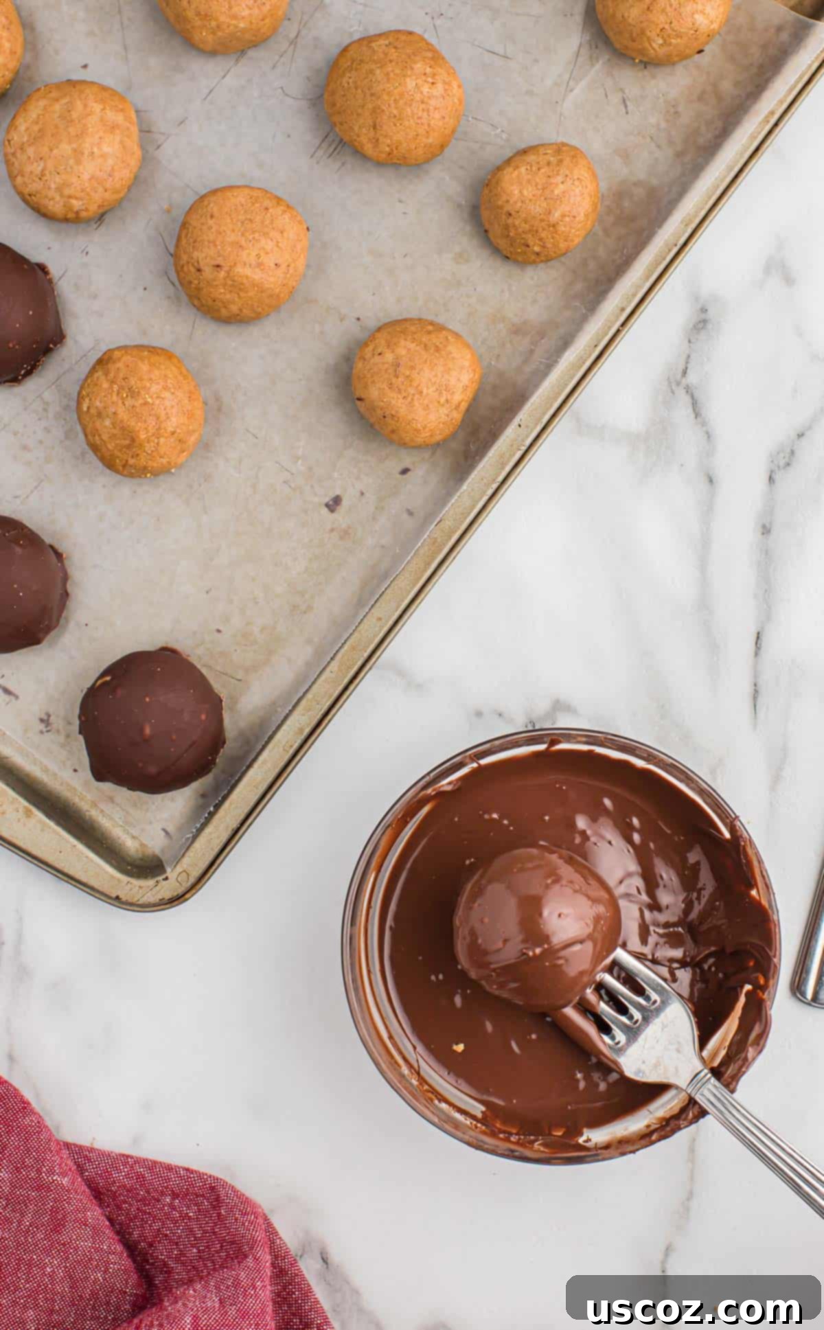 No-Bake Peanut Butter Graham Bites 13 Dipping a peanut butter ball into melted chocolate using a fork, ensuring full coverage.