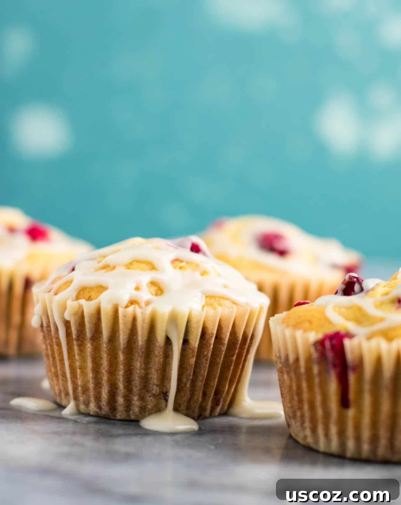 Luscious Cranberry Cream Cheese Muffins 5 Freshly baked cranberry cream cheese muffins cooling on a wire rack, drizzled with a simple white glaze.