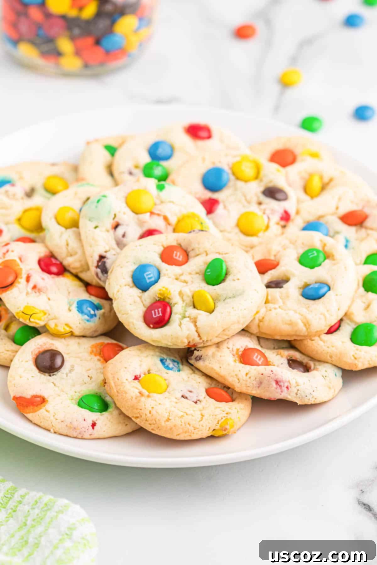 Fluffy White Cake Mix Cookies 12 Close-up of M&M cookies on a white plate, highlighting the delicious textures.