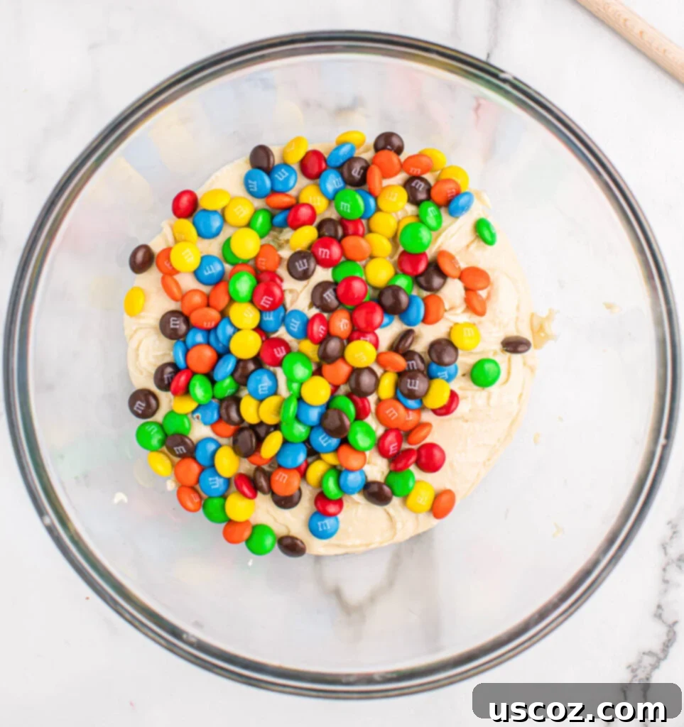 Fluffy White Cake Mix Cookies 6 Adding colorful M&M's to the rich cookie batter, creating a festive look.