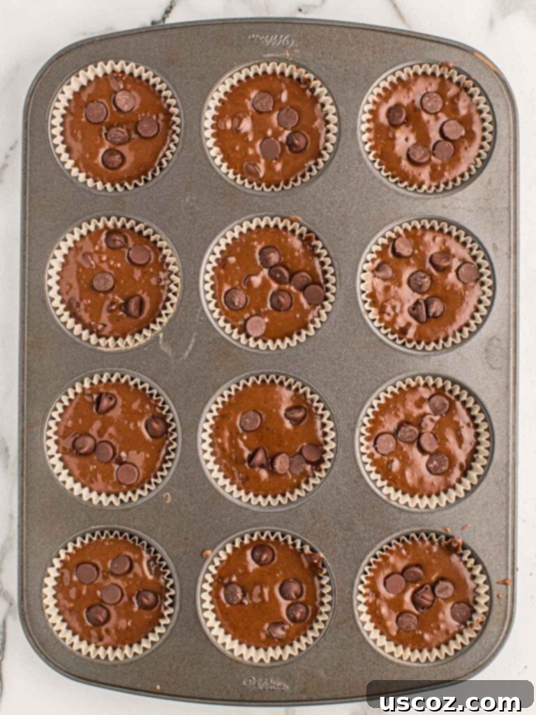 Ultimate Double Chocolate Muffins 10 muffin tin filled with chocolate muffin batter and chocolate chips