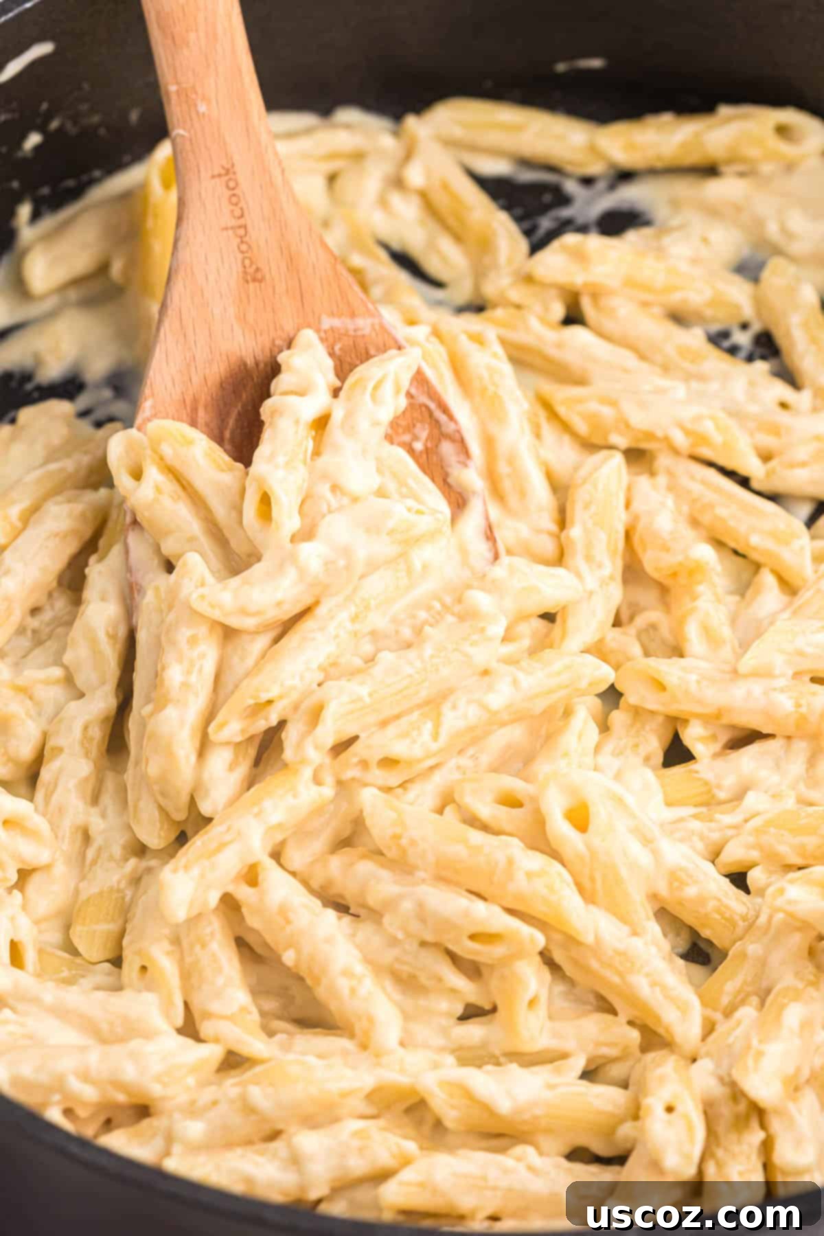 Decadent Creamy Penne 2 A serving of creamy penne pasta on a wooden spoon, showcasing its rich texture