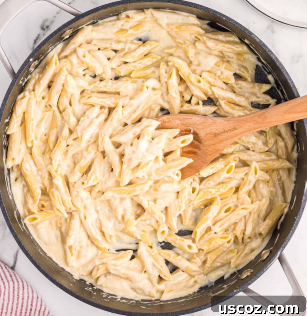 Decadent Creamy Penne 12 A large serving of creamy penne pasta in a skillet, garnished with fresh herbs