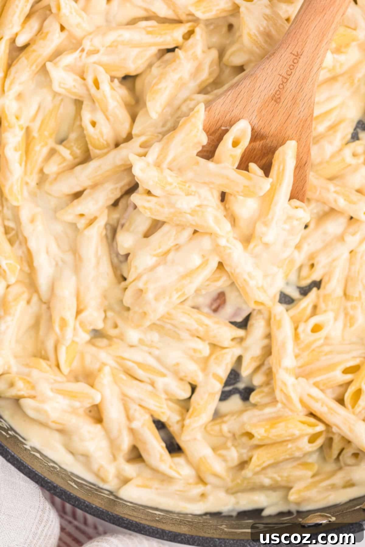 Decadent Creamy Penne 13 A close-up of creamy penne pasta on a wooden spoon, showcasing its rich texture and steam