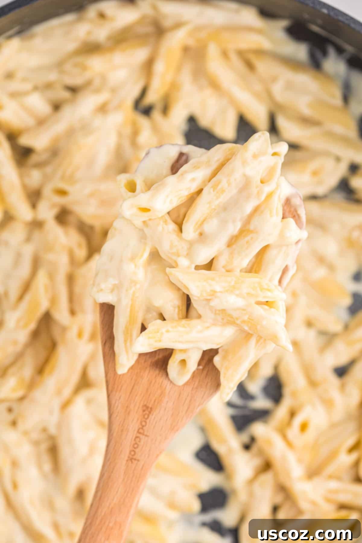 Decadent Creamy Penne 3 Close-up of creamy penne pasta on a wooden spoon, ready to be enjoyed