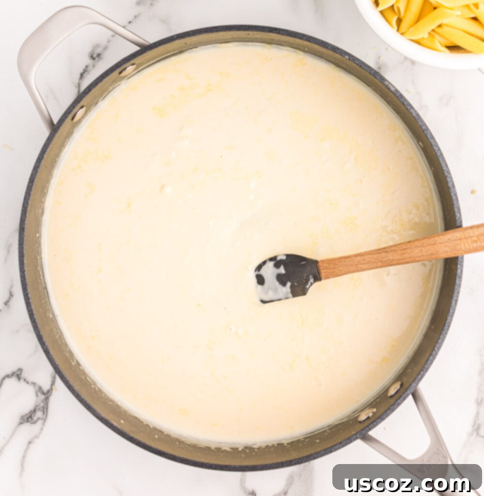 Decadent Creamy Penne 7 A creamy sauce being stirred in a skillet, gently simmering to thicken