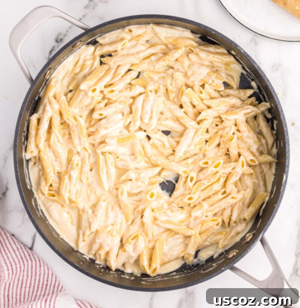 Decadent Creamy Penne 10 Close-up of creamy penne pasta mixed in a skillet, ready to be served