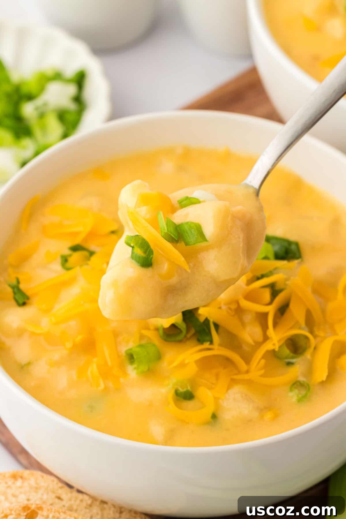 Hearty Potato Comfort 2 A bowl of rich, creamy potato soup generously topped with fresh green onions and shredded cheddar cheese, ready to be enjoyed.