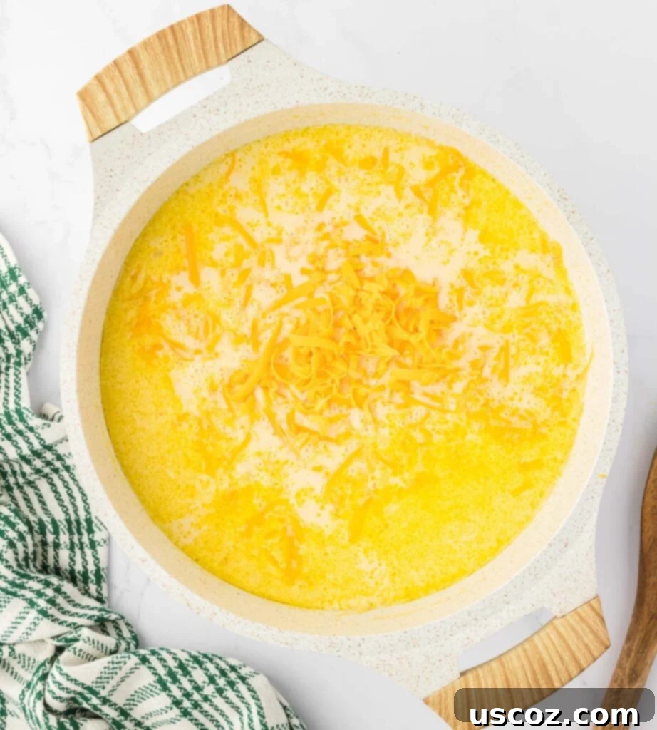 Hearty Potato Comfort 15 Freshly grated cheddar cheese being added to the hot potato soup, ready to melt into a luscious, creamy texture.
