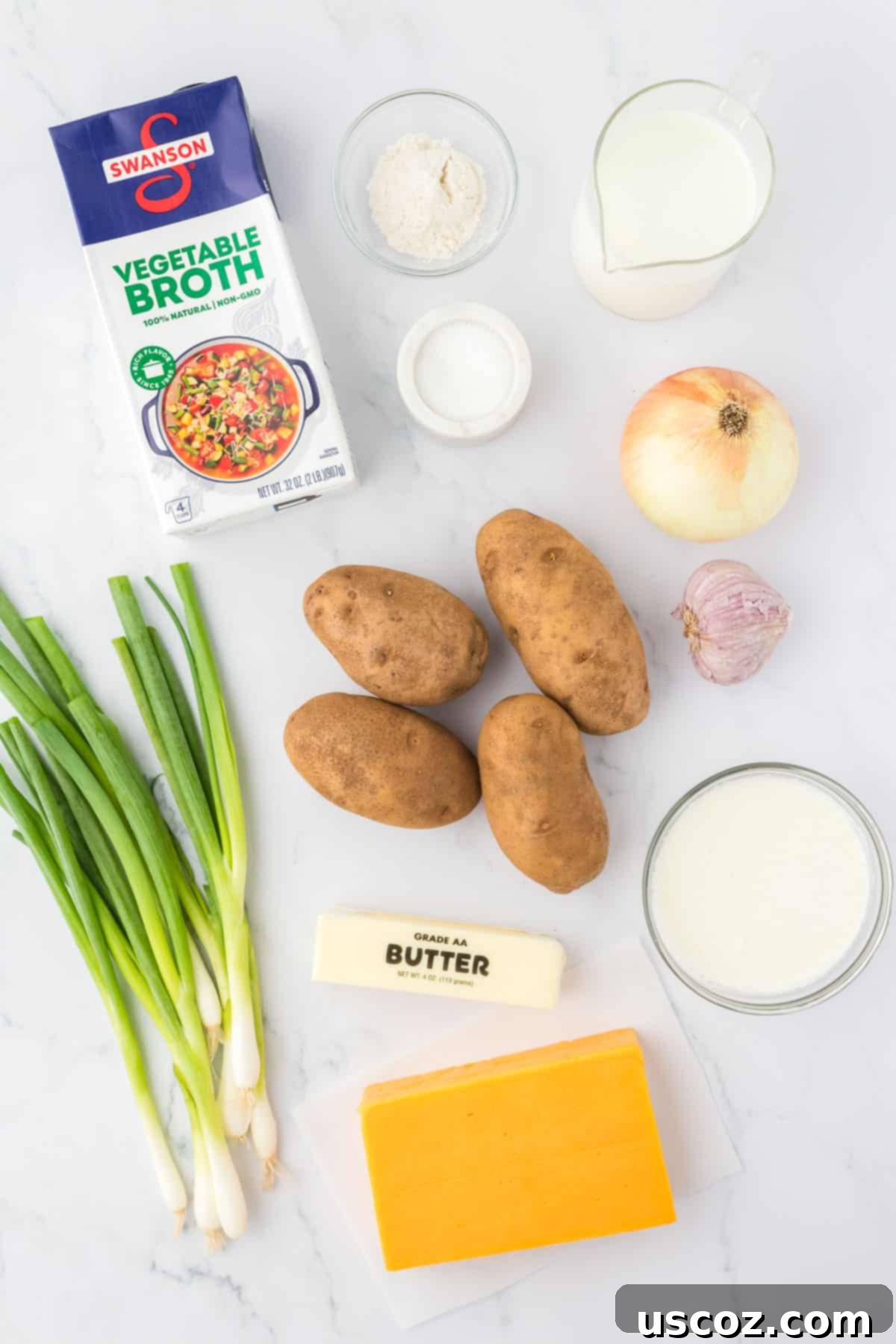 Hearty Potato Comfort 4 A vibrant display of fresh ingredients for vegetarian potato soup including russet potatoes, yellow onion, garlic, vegetable broth, dairy, flour, and cheddar cheese.