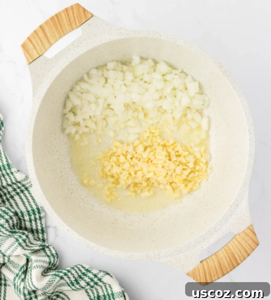 Hearty Potato Comfort 6 Finely diced yellow onion and minced garlic being added to melted butter in a sauce pan.