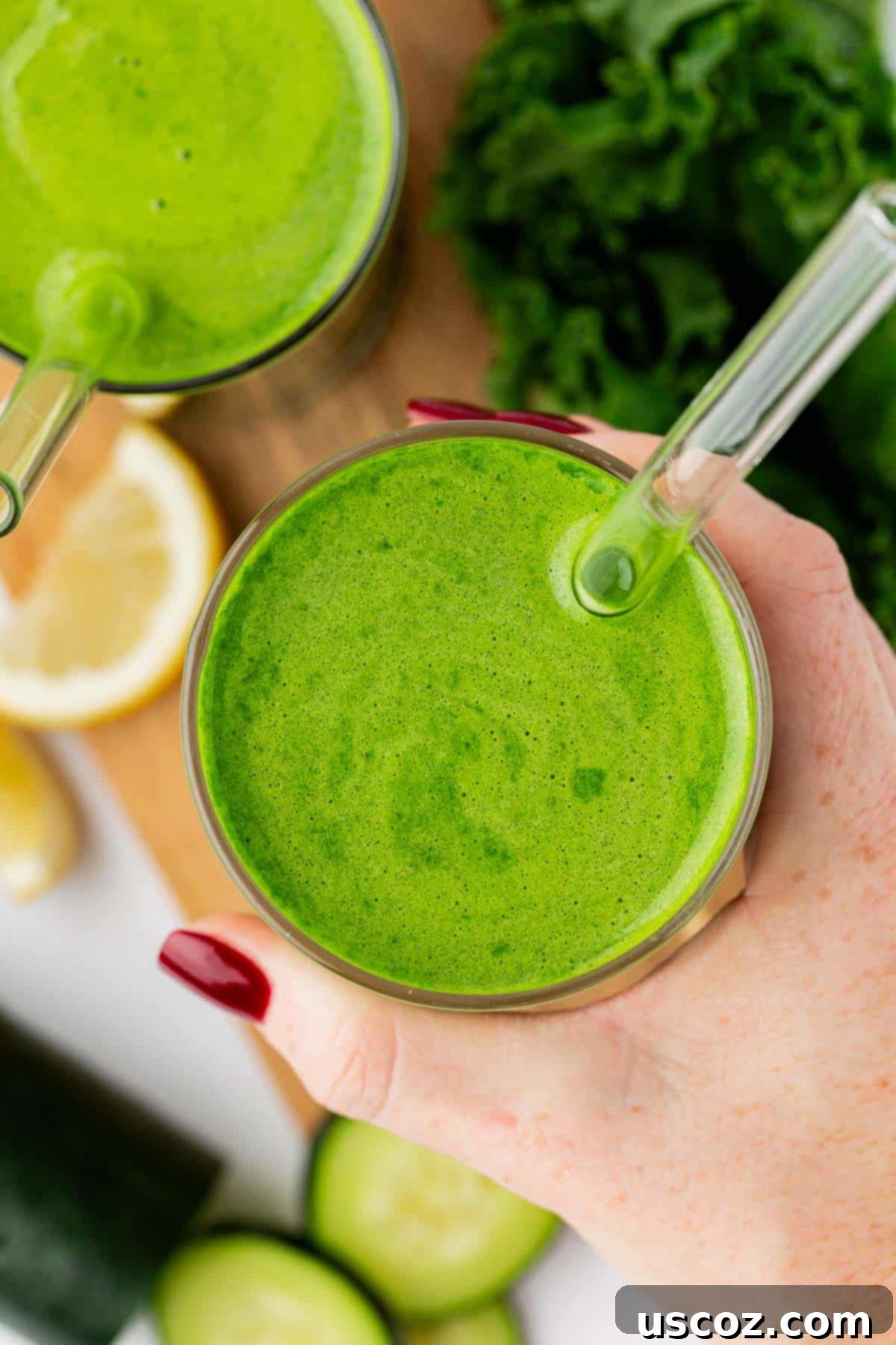 Emerald Elixir 8 A glass of fresh kale juice with a straw, garnished with a cucumber slice, inviting a refreshing sip.