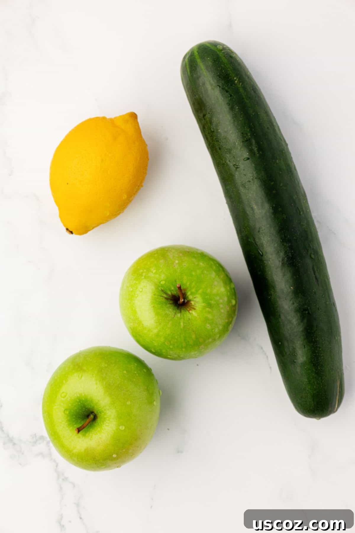Emerald Zest Drink 4 Fresh green apples, a vibrant lemon, and a crisp cucumber laid out as ingredients for juicing.