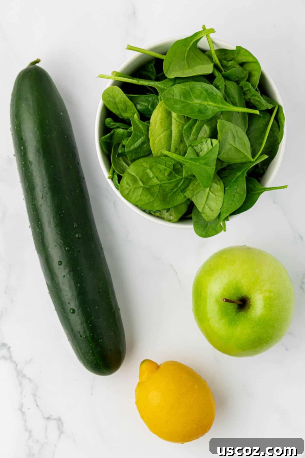 Vibrant Green Elixir 4 Fresh ingredients laid out for juicing: cucumber, spinach, green apple, and lemon