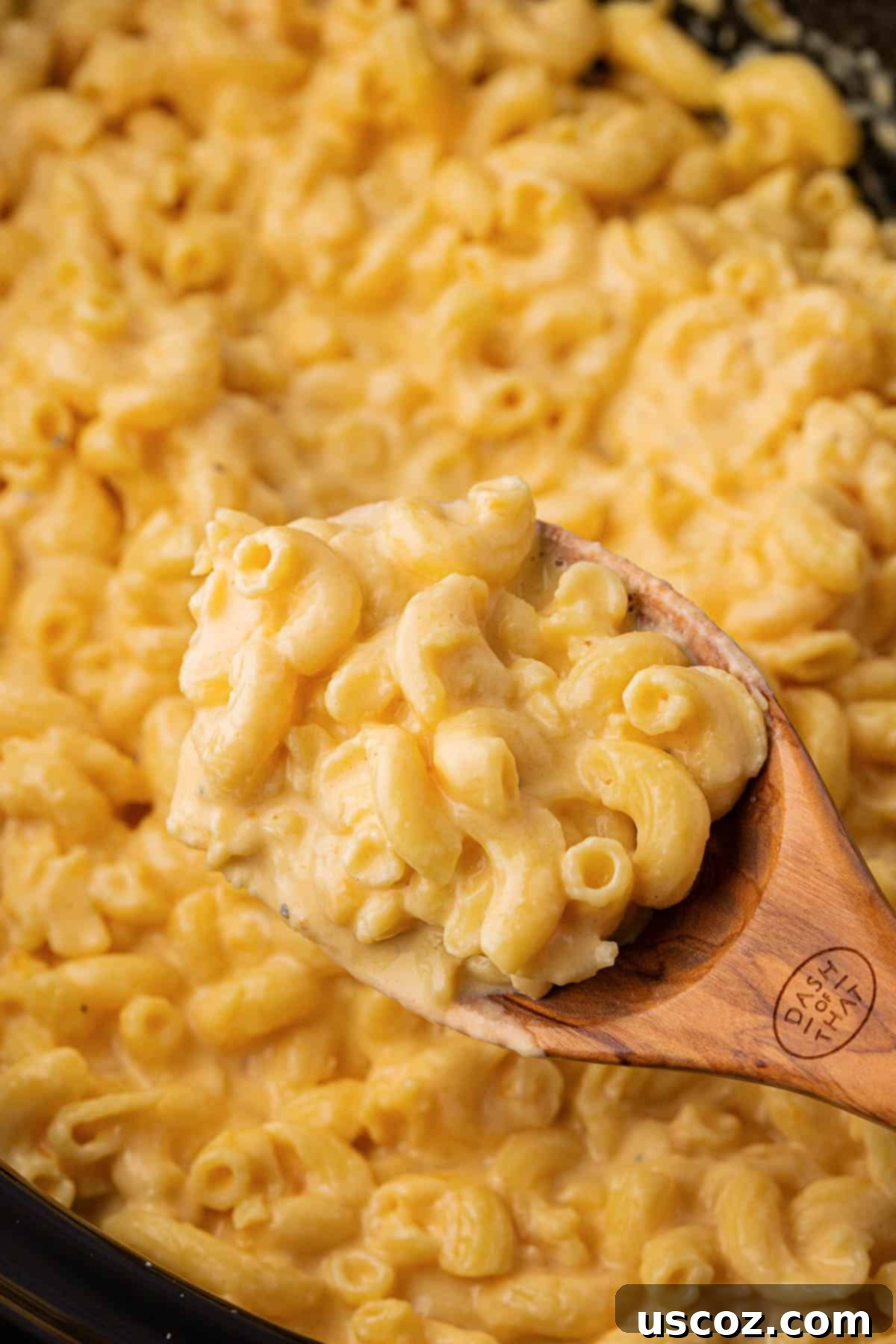 Creamy Slow Cooker Mac and Cheese 12 A wooden spoon scooping decadent mac and cheese from a full crock pot, ready for serving