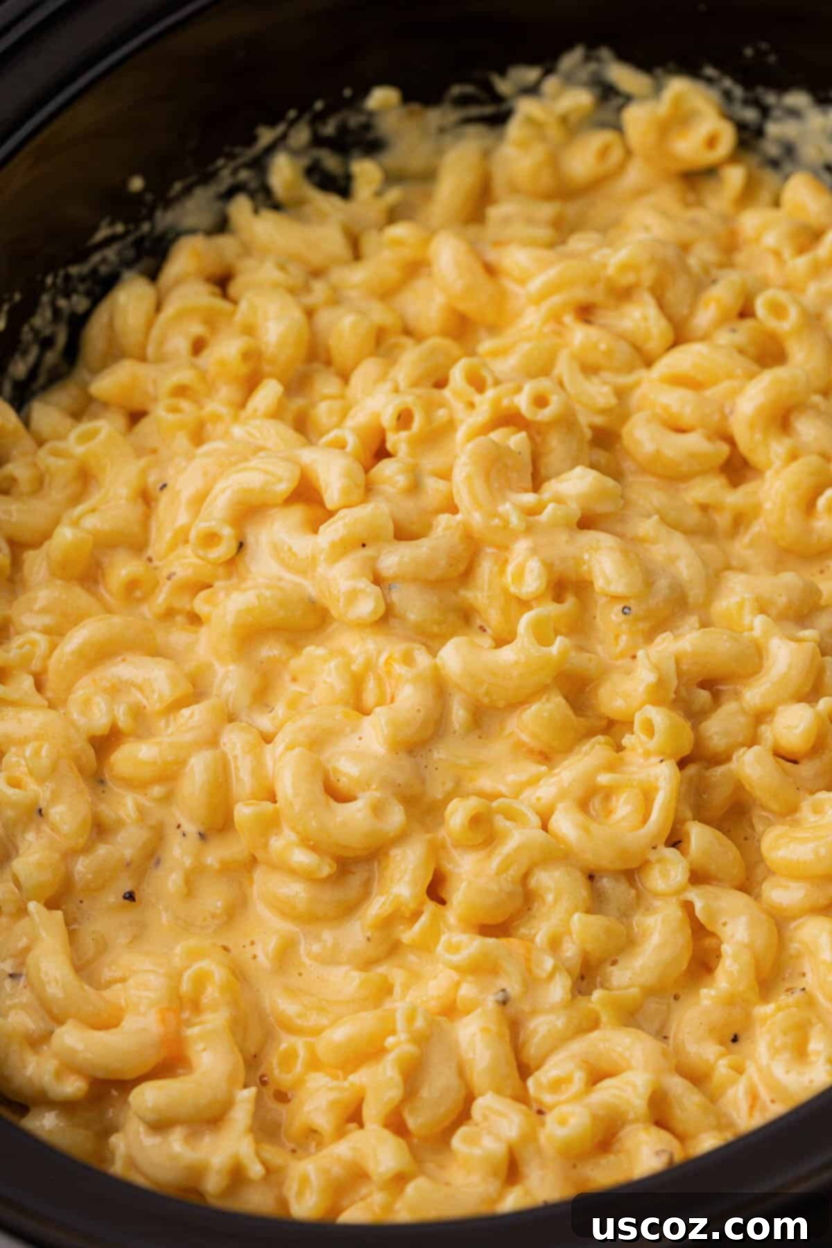 Creamy Slow Cooker Mac and Cheese 16 Close-up of a serving of hot, creamy mac and cheese in a white bowl, garnished with fresh parsley