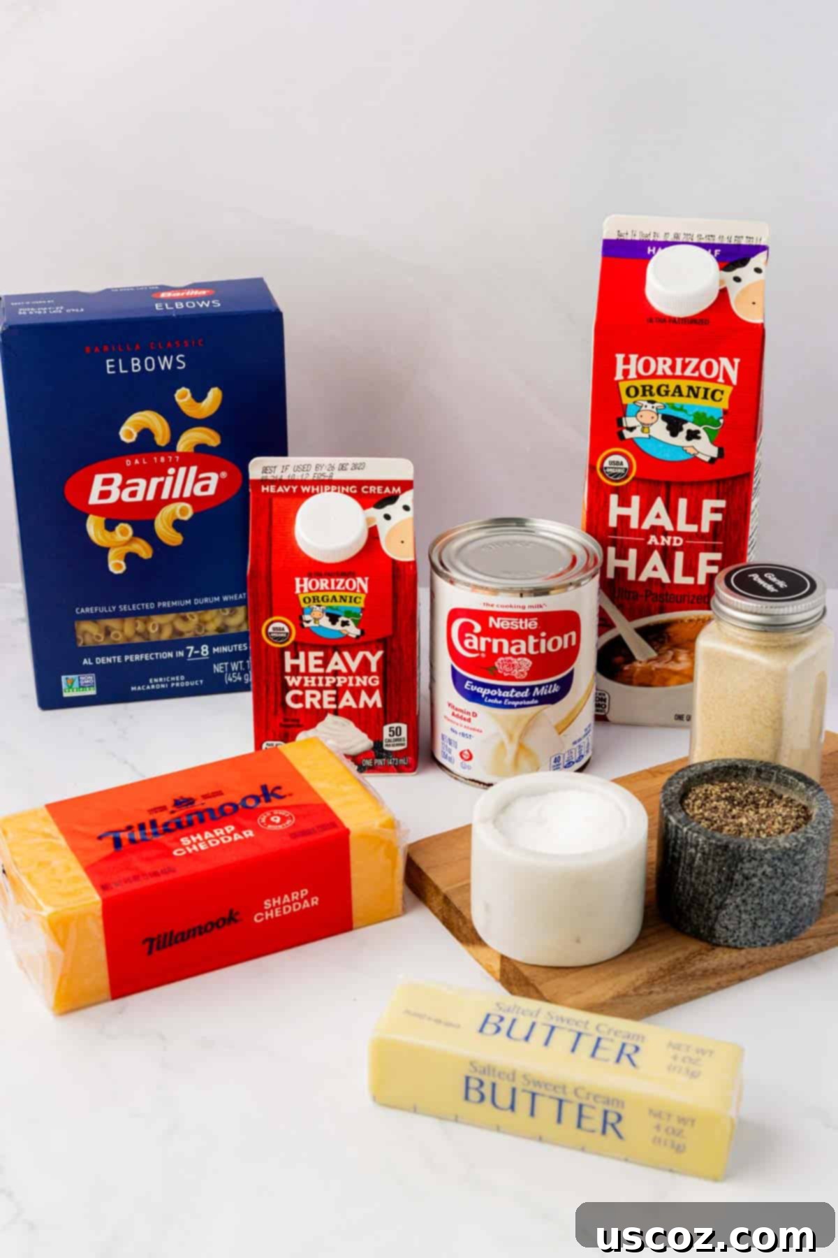 Creamy Slow Cooker Mac and Cheese 4 Arrangement of ingredients including elbow macaroni, various milks, butter, and a block of sharp cheddar cheese on a wooden board