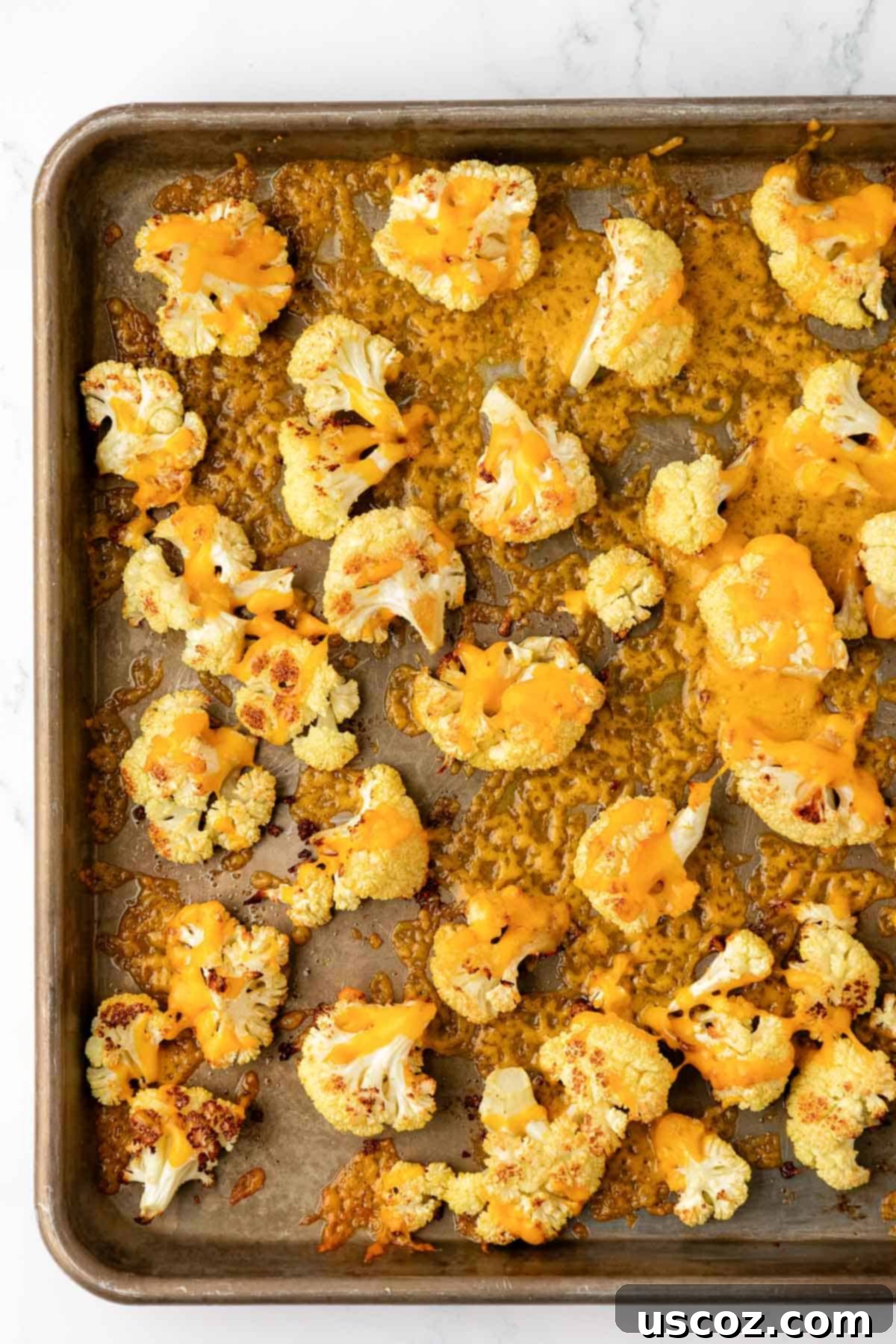 Golden Cheesy Roasted Cauliflower 2 cheesy roasted cauliflower on a baking sheet