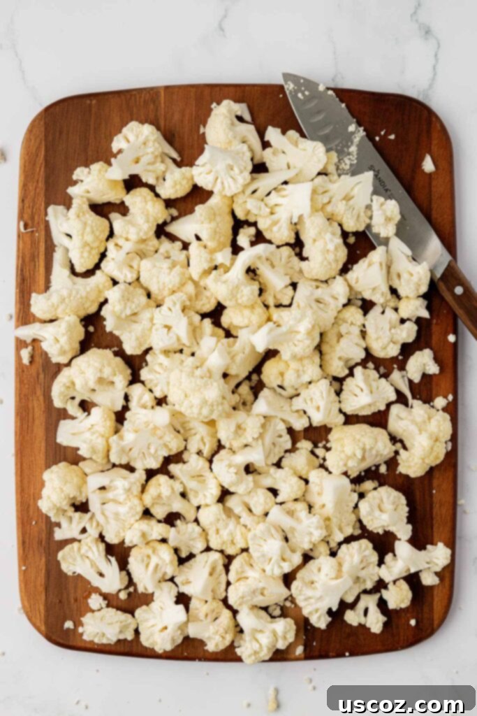 Golden Cheesy Roasted Cauliflower 7 cauliflower florets cut up on a cutting board